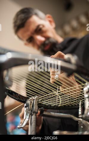 Machine à élingage. Détail des mains de la stringer de tennis tout en tenant l'auge et en faisant la racket de raquette Banque D'Images