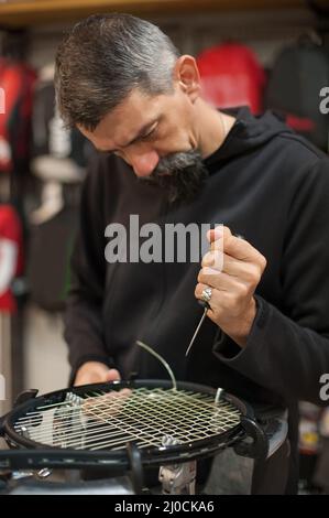 Machine à élingage. Détail des mains de la stringer de tennis tout en tenant l'auge et en faisant la racket de raquette Banque D'Images