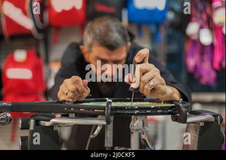 Machine à élingage. Détail des mains de la stringer de tennis tout en tenant l'auge et en faisant la racket de raquette Banque D'Images