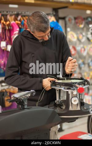 Machine à élingage. Détail des mains de la stringer de tennis tout en tenant l'auge et en faisant la racket de raquette Banque D'Images