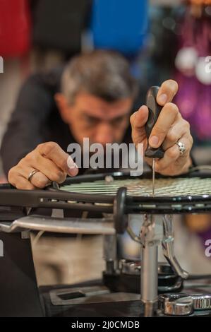 Machine à élingage. Détail des mains de la stringer de tennis tout en tenant l'auge et en faisant la racket de raquette Banque D'Images