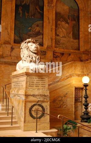 Un lion se trouve sur un piédestal en marbre dans le hall principal de la bibliothèque publique de Boston Banque D'Images