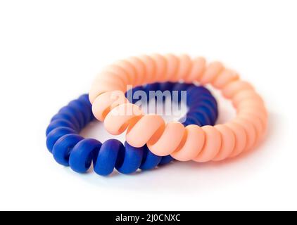 Deux scrunchies isolées sur blanc. Produit de style de cheveux. Serre-câbles à cheveux en spirale bleus et roses doux ou serre-câbles pour cordon téléphonique. Utilisé pour attacher les cheveux dans une queue de cheval avec Banque D'Images