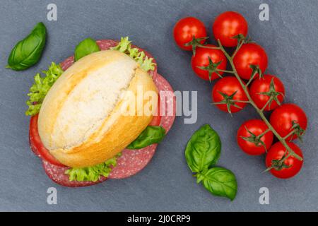 Rouler la baguette surmontée de salami au-dessus de l'assiette en ardoise Banque D'Images