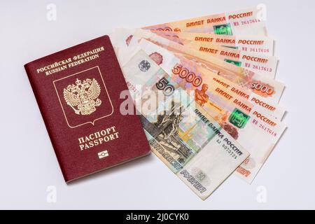 Passeport et billets de banque de la Fédération de Russie (roubles) sur fond blanc. Les concepts de voyages, de sanctions économiques, de transferts d'argent et d'inflation Banque D'Images