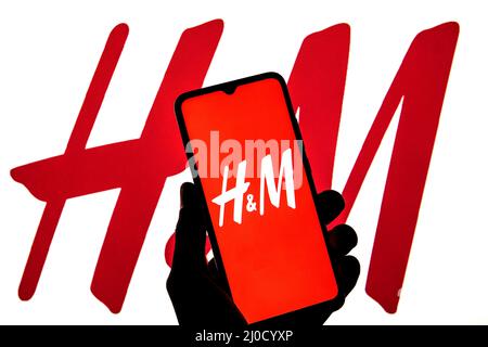 Sur cette photo, le logo H&M est affiché sur un smartphone avec le logo H&M en arrière-plan. Banque D'Images
