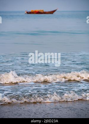 Vagues de la mer d'Arabie avec bateau pêcheur vide en arrière-plan en orientation verticale ou portrait Banque D'Images