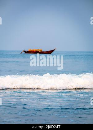 Vagues de la mer d'Arabie avec bateau de pêcheur vide en arrière-plan. Orientation verticale ou portrait Banque D'Images