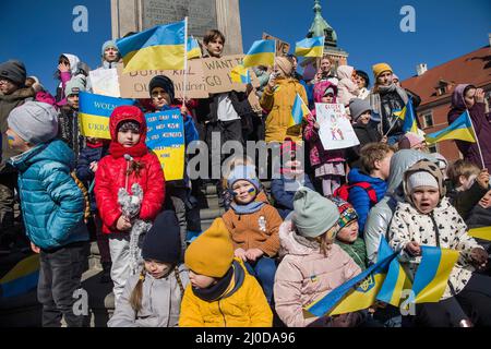 Varsovie, Pologne. 18th mars 2022. Des enfants ukrainiens brandir des pancartes et brandir des drapeaux ukrainiens pendant la manifestation. La "arche des mères ukrainiennes" s'est tenue à Varsovie, qui était également une protestation contre la guerre et le meurtre d'enfants ukrainiens. Les slogans de la marche étaient « World, Help our Children », « Stop the war », « Save Kids of Ukraine » et « Close the Sky ». Principalement des mères ukrainiennes et leurs enfants, qui ont trouvé refuge en Pologne après la guerre, ont pris part à la manifestation. Crédit : SOPA Images Limited/Alamy Live News Banque D'Images