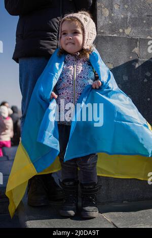 Varsovie, Pologne. 18th mars 2022. Un enfant ukrainien vu enveloppé du drapeau ukrainien pendant la manifestation. La "arche des mères ukrainiennes" s'est tenue à Varsovie, qui était également une protestation contre la guerre et le meurtre d'enfants ukrainiens. Les slogans de la marche étaient « World, Help our Children », « Stop the war », « Save Kids of Ukraine » et « Close the Sky ». Principalement des mères ukrainiennes et leurs enfants, qui ont trouvé refuge en Pologne après la guerre, ont pris part à la manifestation. Crédit : SOPA Images Limited/Alamy Live News Banque D'Images