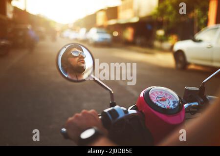 Prêt à prendre la route. Photo d'un homme réfléchissant sur le miroir latéral de son scooter. Banque D'Images