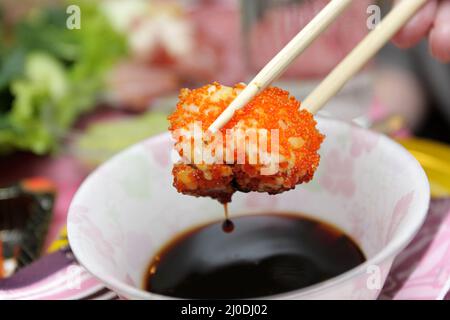 Les sushis uramaki dans une sauce soja Banque D'Images