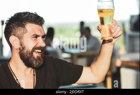 Homme avec la barbe boire de la bière. Homme tenant une tasse de bière. Gars au comptoir du bar. Hipster se détendre au pub. Beau barbu homme de boire de la bière. Banque D'Images