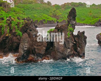 Les visiteurs explorent les falaises de Lava au parc national de Waianapanapa à Hana, Hawaï, sur l'île de Maui Banque D'Images