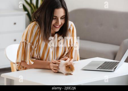 Belle jeune femme avec mignon cobaye à la maison Banque D'Images