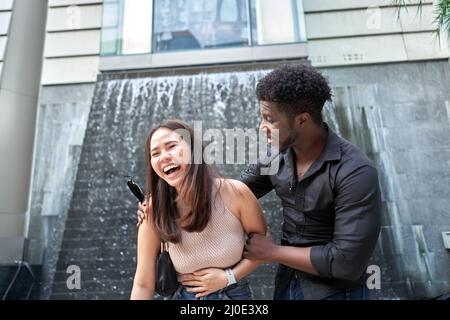 Femme asiatique qui rit à côté d'un ami africain dans un centre commercial Banque D'Images