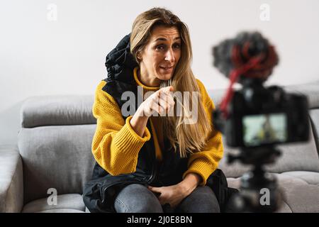 Jeune femme attrayante blogger ou vlogger regardant et pointant vers l'appareil photo et parlant sur le tournage vidéo avec la technologie. Personnes influentes sur les médias sociaux Banque D'Images