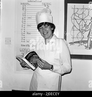 Prudence Leith (également connu sous le nom de Prie Leith) photographié dans la cuisine, devant un tableau de poids et mesures, souriant, Avec le livre de cuisine qu'elle a co-écrit.Voir le reste de cette série avec Prue avec sa concurie Caroline Waldergrave Prue et Caroline sont les auteurs d'un nouveau livre de cuisine - Leith's Cookery course Book 1 - et sont vus se préparant ce soir à l'arrivée de l'un de leurs cours de cuisine en soirée. Photo prise le 24th octobre 1979 Banque D'Images