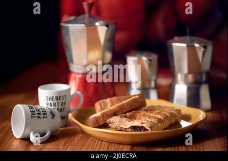Des cafetières italiennes et des pâtisseries sur une table avec des tasses de café, des détails sur les tasses et des réflexions sur 3 tailles de cafetières Banque D'Images