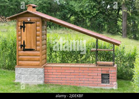 Petit fumoir maison avec base en pierre et cheminée d'entrée longue Banque D'Images