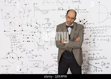 Mathématicien caucasien d'âge moyen debout devant des équations mathématiques sur un mur blanc Banque D'Images