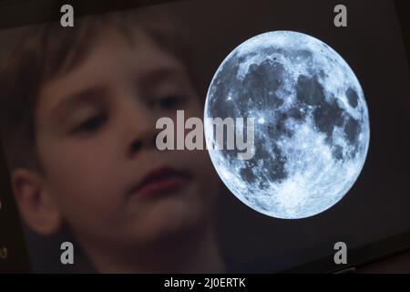 Reflet d'un jeune garçon regardant la lune sur une tablette Banque D'Images