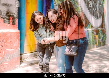 Trois jeunes femmes descendent dans la rue, elles sourient, jouent et ont un bon moment. Banque D'Images