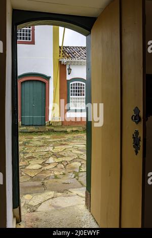 Rue en pierre et maisons anciennes vues par une vieille porte en bois Banque D'Images