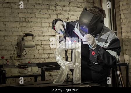 Soudeur soudant une pièce métallique dans un environnement industriel, portant un équipement de protection standard. Banque D'Images