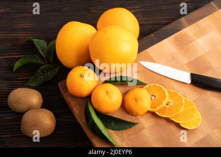 Tranches d'orange et d'autres fruits sur une planche à découper en bois Banque D'Images