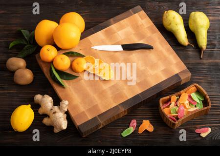 Tranches d'orange et d'autres fruits sur une planche à découper en bois Banque D'Images