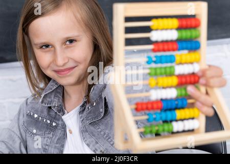 La fille résout la tâche donnée dans la salle de classe. L'écolière écrit diligemment dans un bloc-notes. Banque D'Images