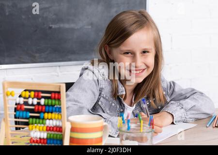 La fille résout la tâche donnée dans la salle de classe. L'écolière écrit diligemment dans un bloc-notes. Banque D'Images