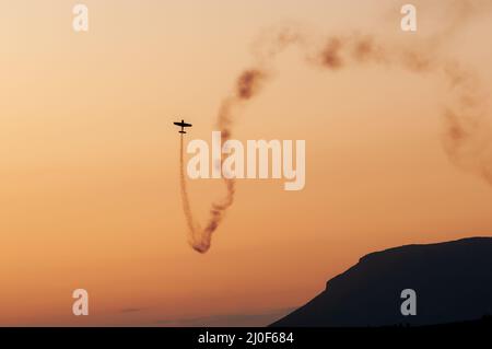 Avion effectuant des acrobaties aériennes pendant le coucher du soleil à la semaine de vol d'Athènes en Grèce. Banque D'Images