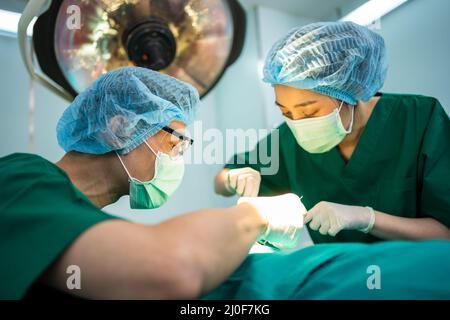 L'équipe de chirurgiens professionnels asiatiques effectuant la chirurgie dans la salle d'opération, le chirurgien, les assistants, et les infirmières effectuant la chirurgie sur un patient, voiture de santé Banque D'Images