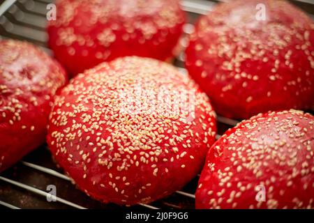 Petits pains à hamburger faits maison, rouges et frais, avec vue sur le dessus du sésame. Placé sur la grille métallique. Banque D'Images