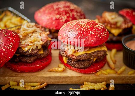 Un ensemble de petits pains rouges de délicieux hamburgers faits maison de bœuf, bacon, fromage, oignon grillé sur un rouillé foncé Banque D'Images