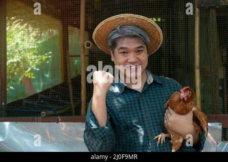 Les agriculteurs asiatiques organisent des poules. Dans un élevage de poulets dans leur propre région avec un geste heureux Banque D'Images