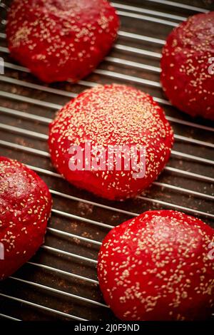 Petits pains à hamburger faits maison, rouges et frais, avec vue sur le dessus du sésame. Placé sur la grille métallique. Banque D'Images