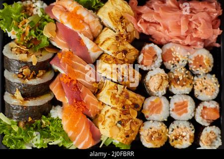 Gros plan de divers ensembles de sushis dans une boîte de livraison en plastique noir. Vue de dessus Banque D'Images