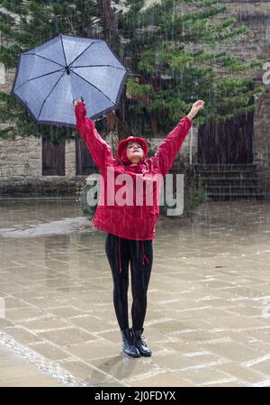 Jeune femme heureuse avec un parapluie dansant sous la pluie. Banque D'Images