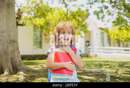 Retour à l'école. Enfant avec sacs à dos debout dans le parc près de l'école. Élèves avec des livres et des sacs à dos à l'extérieur. Banque D'Images
