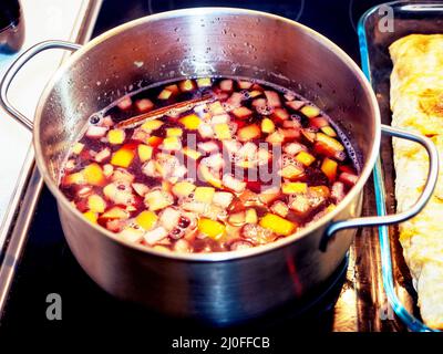 Le vin chaud avec beaucoup de fruits est cuit une poêle debout sur une cuisinière électrique Banque D'Images