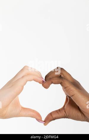 La forme d'un coeur composé de deux mains de races différentes, africaine et européenne. Ce coeur de l'amour est un message pour tous Banque D'Images