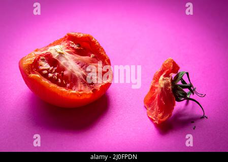 Tranche de légume de tomate rouge pourri isolée sur fond magenta Banque D'Images