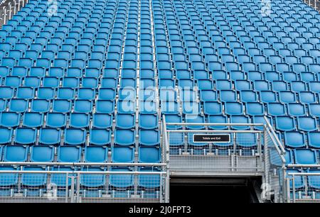 Chaises de stade vides en plastique bleu rangées Banque D'Images