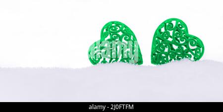 Bannière avec deux coeurs en velours vert dans une dérive de neige sur fond blanc avec un espace de copie Banque D'Images