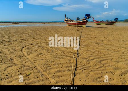 Les bateaux thaïlandais traditionnels à longue queue en bois (Rua Hang Yao) amarrés sur le sable à la petite jetée avec ciel bleu et petit fond d'île Banque D'Images