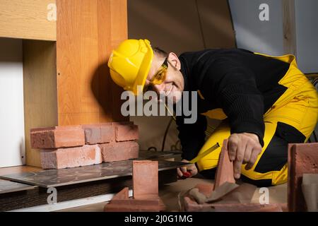 Le travailleur de la construction se joint à un autre carreau décoratif en forme de brique pour poursuivre le travail prévu. Travailleur de la construction Banque D'Images