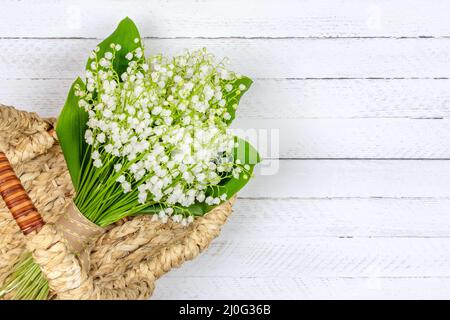 Bouquet de Lily de la vallée fleurit dans un panier sur fond blanc en bois avec un espace copie vue de dessus Banque D'Images